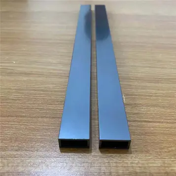 Two black anodized standard rectangular aluminum extrusion profiles placed on wooden surface, showing premium surface finish and hollow section, ideal for structural and architectural applications by Yoverd Aluminium