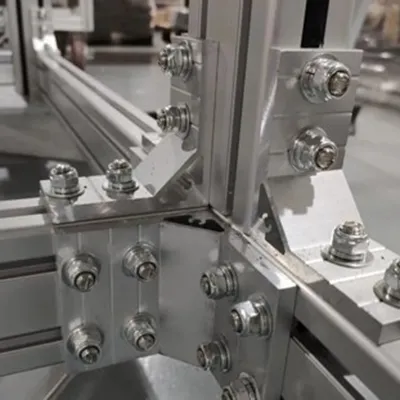 Close-up view of silver T-slot aluminum extrusion profiles securely connected with corner brackets, bolts and nuts for strong modular machine frame systems By Yoverd Aluminium
